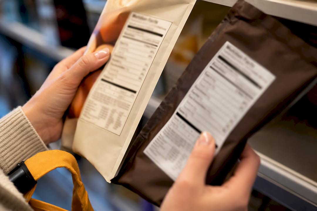 Hands comparing anonymous food label panels